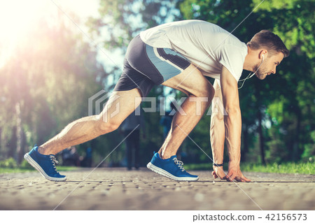 Muscular athlete preparing for race outdoors  42156573