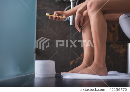 Woman using phone in lavatory Woman using phone in lavatory 42156770