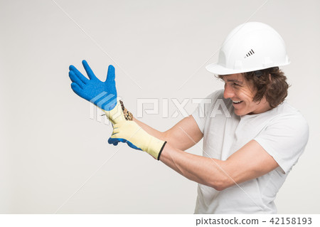 portrait of happy builder in helmet wearing glove. 42158193