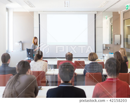 Woman giving presentation in lecture hall at university. 42158203