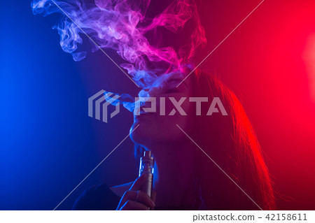 Close up portrait of vaping girl in neon blue and red light. Close up portrait of vaping girl in neon blue and red light. 42158611