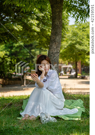 Woman resting in the shade of a tree Woman resting in the shade of a tree 42159591
