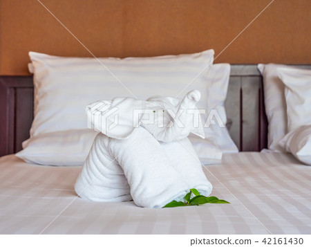 White elephant towel and comfortable pillow on bed 42161430