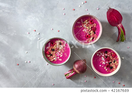 Beetroot smoothies with berries, granola and sesame seeds in a plate on a gray concrete background Beetroot smoothies with berries, granola and sesame seeds in a plate on a gray concrete background 42167689