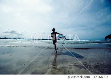 woman surfer with surfboard running on beach woman surfer with surfboard running on beach 42168994