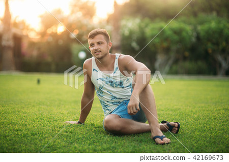 Smiled man in shorts and shirt in summer time walks near the park 42169673