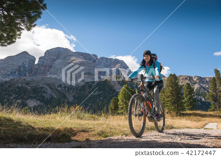 pretty young woman on bicycle in italien dolomites 42172447