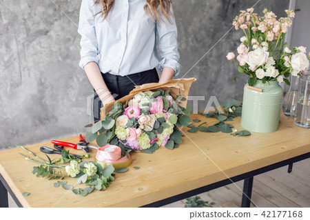 Woman florist creating beautiful bouquet in flower shop. Working in flower shop. Girl assistant or Woman florist creating beautiful bouquet in flower shop. Working in flower shop. Girl assistant or 42177168