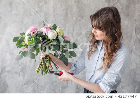 Woman florist creating beautiful bouquet in flower shop. Working in flower shop. Girl assistant or 42177447