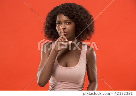 The young woman whispering a secret behind her hand over red background The young woman whispering a secret behind her hand over red background 42182381
