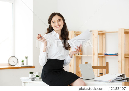 Happy young business woman or secretary holding document in modern office Happy young business woman or secretary holding document in modern office 42182407