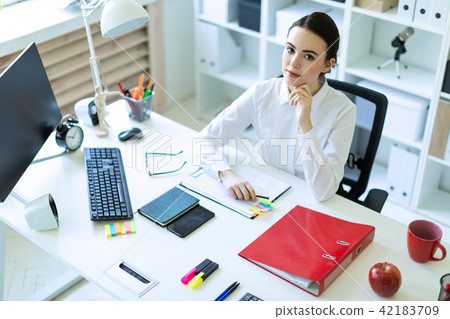 A young girl is sitting at the computer desk in the office. A young girl is sitting at the computer desk in the office. 42183709