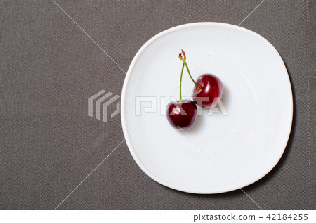 Two cherries on a white plate 42184255