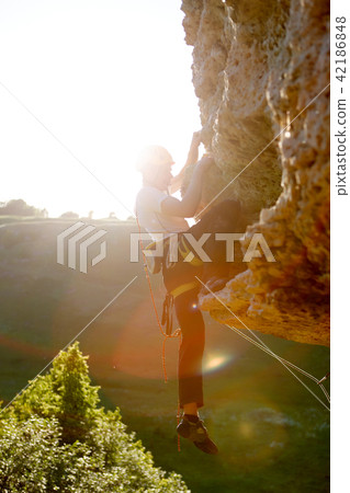Image of rock climber in helmet climbing up mountain 42186848