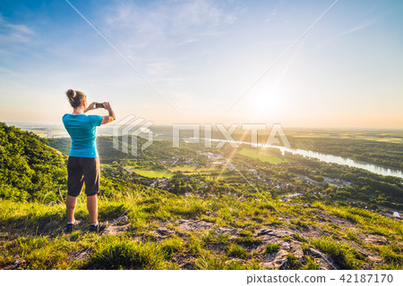 A Girl Taking Photograph of the Sunset 42187170