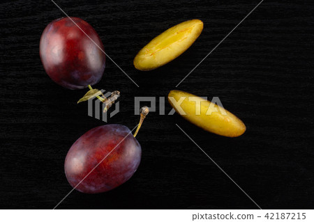Fresh Raw vibrant plums on black wood Fresh Raw vibrant plums on black wood 42187215