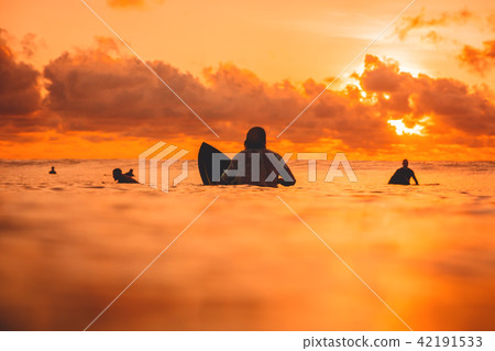 Surfers on line up in ocean at sunset or sunrise. Surfers on line up in ocean at sunset or sunrise. 42191533