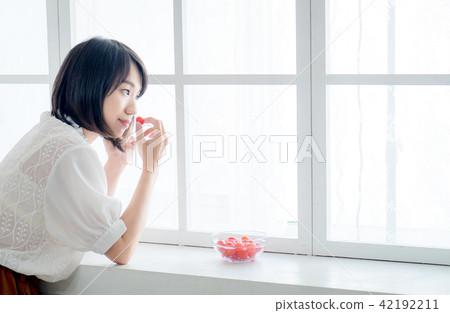 Woman having breakfast on window 42192211