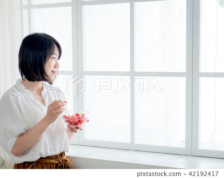 Woman having breakfast on window 42192417