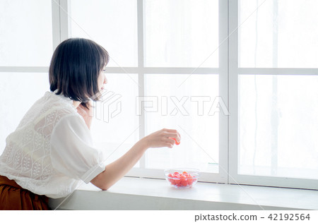 Woman having breakfast on window 42192564