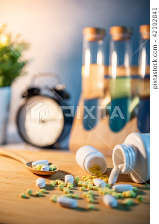Pills spilling out of pill bottles on wooden table 42192841