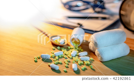 Pills spilling out of pill bottle on doctor desk 42192861