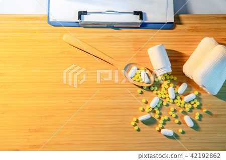 Pills spilling out of bottle with doctor clipboard 42192862