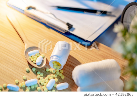 Pills spilling out of pill bottle on doctor desk 42192863