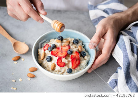 Eating healthy breakfast oatmeal porridge with fresh berries and nuts Eating healthy breakfast oatmeal porridge with fresh berries and nuts 42195768