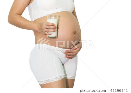 Pregnant woman hand holding fresh milk full glass on belly. 42196341