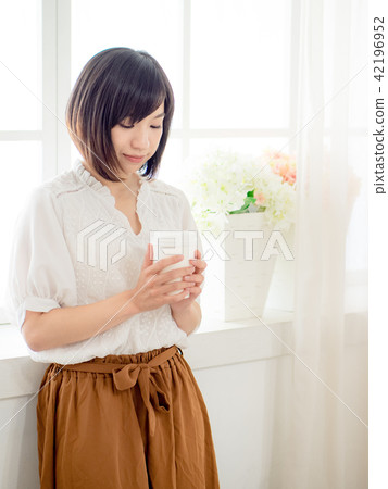 young woman standing in front of window young woman standing in front of window 42196952