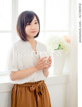 young woman standing in front of window young woman standing in front of window 42196958