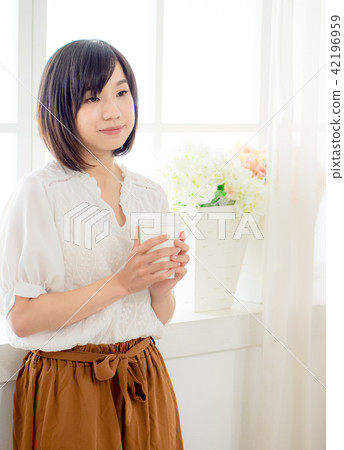 young woman standing in front of window young woman standing in front of window 42196959