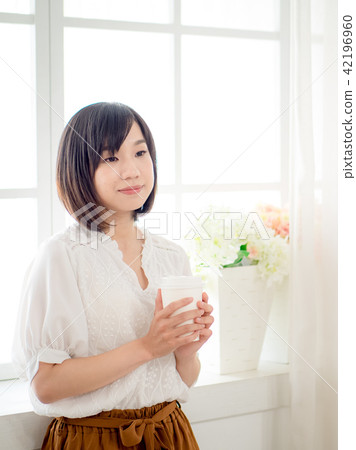 young woman standing in front of window young woman standing in front of window 42196960
