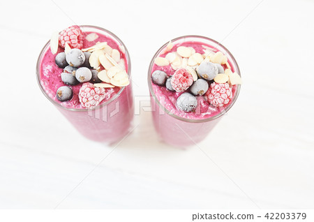 Two glasses of pink fruit smoothies milkshake or smoothie or cocktail on a white wooden background Two glasses of pink fruit smoothies milkshake or smoothie or cocktail on a white wooden background 42203379