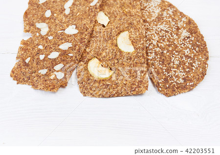Bread with flaxseeds and almonds on a white wooden background. Useful dietary raw bread vegan 42203551
