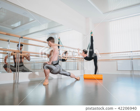Preparation of body before performance in ballet studio. Male dancer and ballerina warming up near 42206940