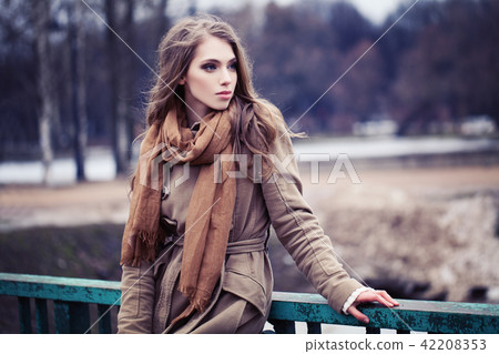 Young woman in brown coat outdoors Young woman in brown coat outdoors 42208353