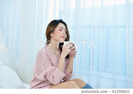 Winter Concept. Beautiful woman is relaxing in a white bedroom. Winter Concept. Beautiful woman is relaxing in a white bedroom. 42208681