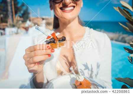 Woman enjoying the food at the pool catering in beach house Woman enjoying the food at the pool catering in beach house 42208861