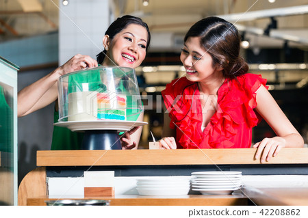 Cheerful woman happy to eat together with her best friend Cheerful woman happy to eat together with her best friend 42208862
