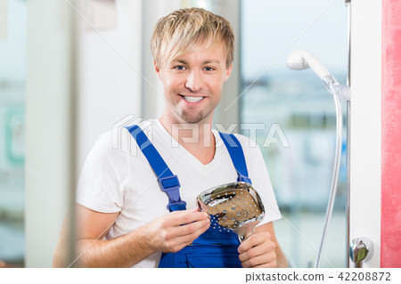 Portrait of a cheerful maintenance worker holding a faucet 42208872