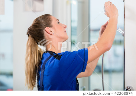 Skilled female worker checking a showerhead in a modern sanitary ware shop 42208874