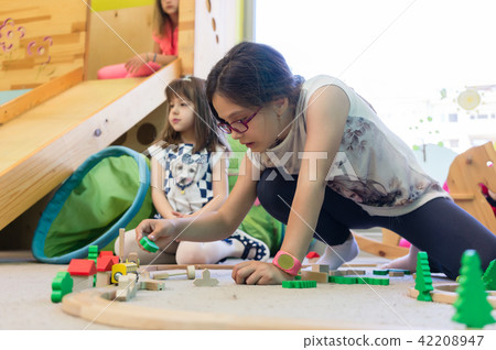 Girl playing with a wooden train circuit in the kindergarten 42208947