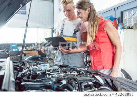 Auto mechanic showing to a customer the engine error codes Auto mechanic showing to a customer the engine error codes 42208995