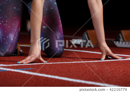woman sprinter leaving starting blocks on the athletic track. exploding start on stadium with 42210779