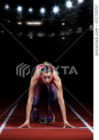 woman sprinter leaving starting blocks on the athletic track. exploding start on stadium with 42210852