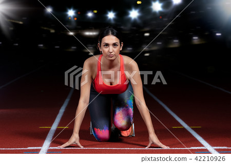 woman sprinter leaving starting blocks on the athletic track. exploding start on stadium with 42210926