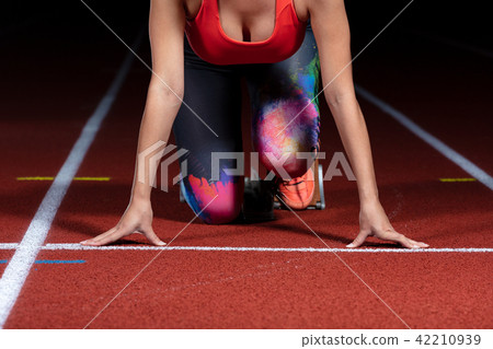 woman sprinter leaving starting blocks on the athletic track. exploding start on stadium with 42210939