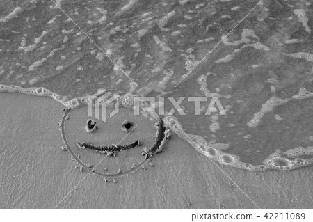 On the sand drawn a smiley face and a wave washes On the sand drawn a smiley face and a wave washes 42211089